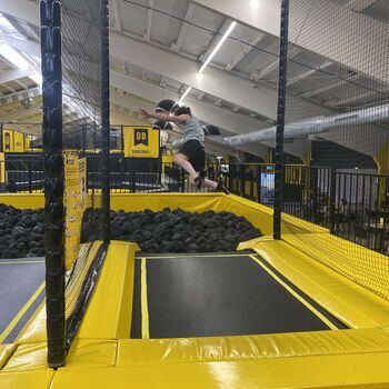 Ein Junge springt fröhlich auf einem Trampolin in einer Spielfläche mit Schaumstoffblöcken | © Name.