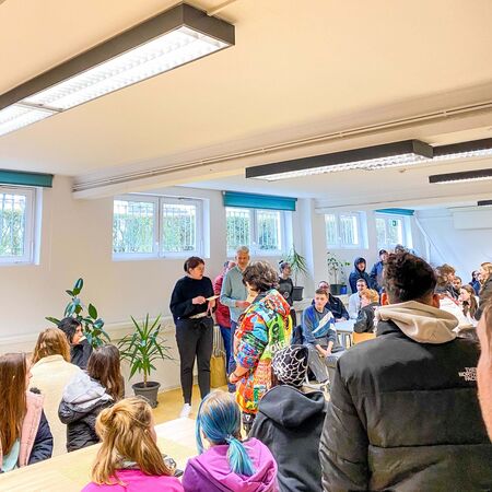 Eine Gruppe von Menschen sitzt in einem hellen Raum und nimmt an einer Beratungssitzung teil.