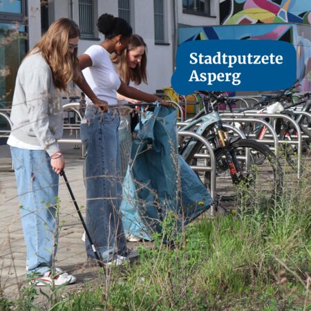 Junge Menschen sammeln Müll bei der Stadtputzete in Asperg neben Fahrradständern und einem bunten Wandbild.