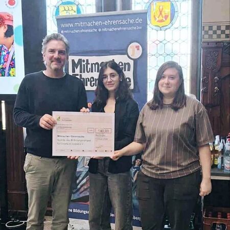 Drei Personen präsentieren stolz einen Scheck im Rahmen der Mitmachen Ehrensache-Initiative.