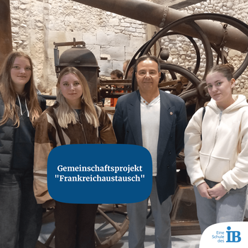 Vier Personen posieren vor einer historischen Maschine für das Gemeinschaftsprojekt "Frankreichaustausch".