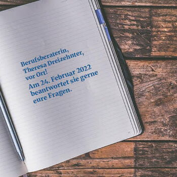 Ein offenes Notizbuch mit einem blauen Stift liegt auf einem Holztisch, der Text informiert über eine Beratung am 24. Februar 2022.