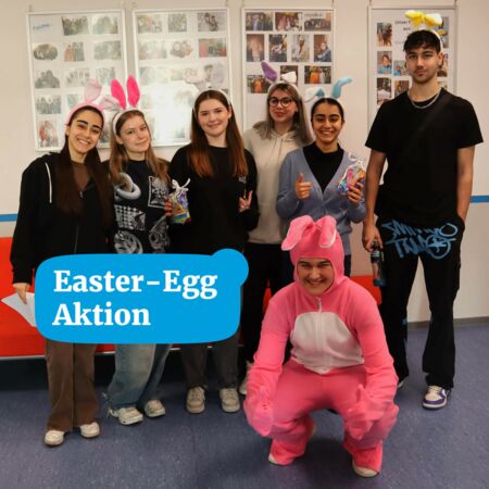 Eine Gruppe junger Menschen mit Hasenohren posiert fröhlich bei einer Osteraktion, während eine Person im pinken Kostüm kniet.