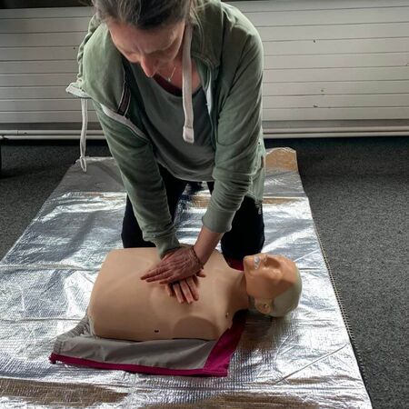 Eine Frau übt Erste-Hilfe-Maßnahmen an einer Puppe auf einer Rettungsdecke während eines PädTag-Workshops.