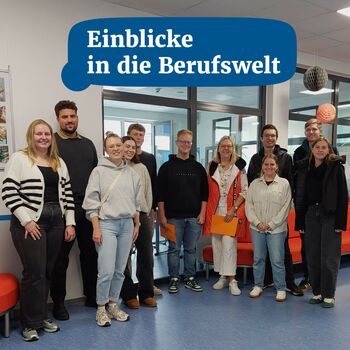 Eine Gruppe von Menschen steht lächelnd in einem Raum, der für den Berufs- und Studientag dekoriert ist.