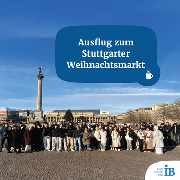 Eine große Gruppe steht vor der Stuttgarter Weihnachtsmarkt-Kulisse mit einer Säule und historischem Gebäude.