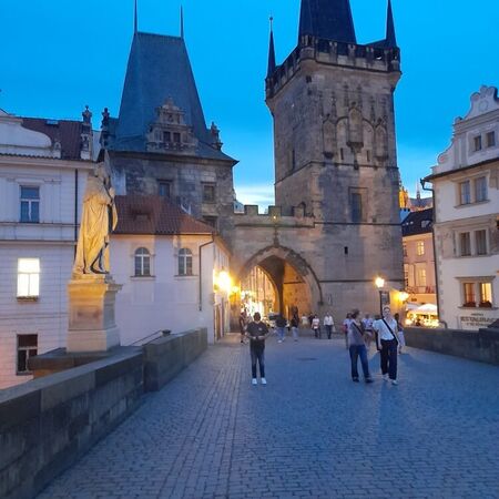 Die Karlsbrücke zeigt Menschen, die bei Dämmerung die historische Architektur bewundern.