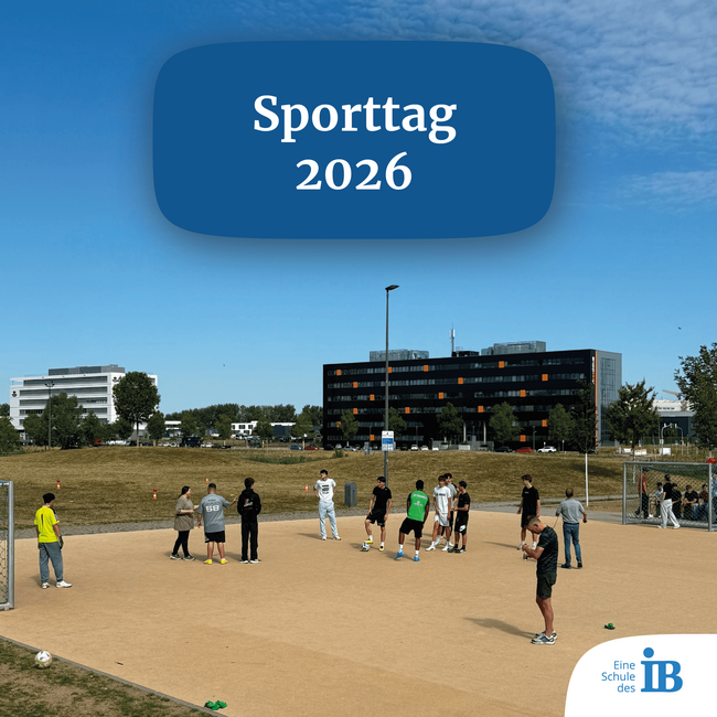 Sporttag 2026: Schüler spielen im Freien Fußball auf einem Sportplatz unter blauem Himmel und Sonnenschein.