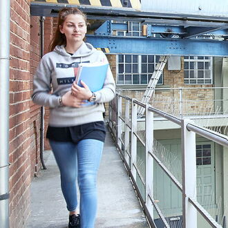 junge Frau im Eingangsbereich der IB Esslingen mit Arbeitsmappen auf dem Arm