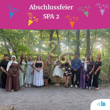 Eine Gruppe von Absolventen feiert die Abschlussfeier SPA 2 im Wald mit Luftballons in Form der Zahl 26.