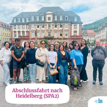 Gruppe von Menschen posiert fröhlich während ihrer Abschlussfahrt nach Heidelberg auf einem Platz.