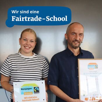 Zwei Personen präsentieren stolz die Urkunde ihrer Fairtrade-Schule in einem modernen Raum.