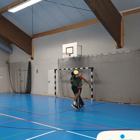 Zwei Spieler feiern ein Tor während eines spannenden Fußballturniers in einer Sporthalle.