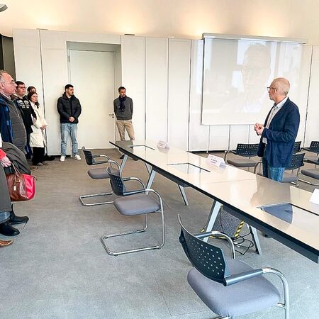 Ein Mann hält eine Präsentation vor einer Gruppe von Menschen in einem modernen Konferenzraum.