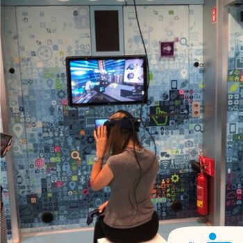 Eine Person testet Virtual Reality in einem modernen, technologieorientierten Raum mit buntem Hintergrund. | © IB