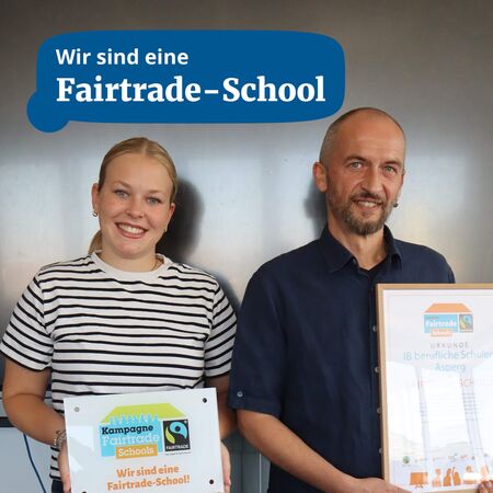 Zwei Personen präsentieren stolz die Urkunde ihrer Fairtrade-Schule in einem modernen Raum.