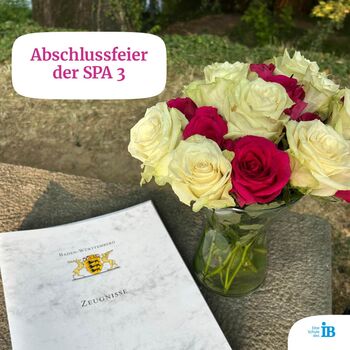 Blumen und Zeugnisse zur Abschlussfeier der SPA 3 auf einem Tisch im Freien.