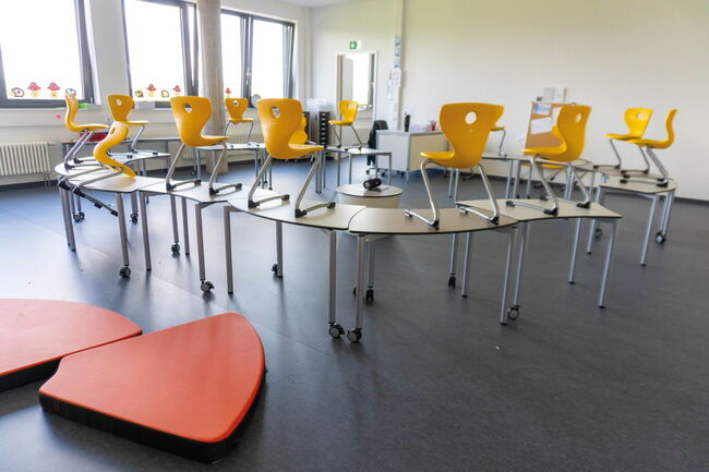 Gelbe Stühle stehen auf Tischen in einem hellen Klassenzimmer der Grundschule Flugfeld, bereit für den nächsten Schultag.