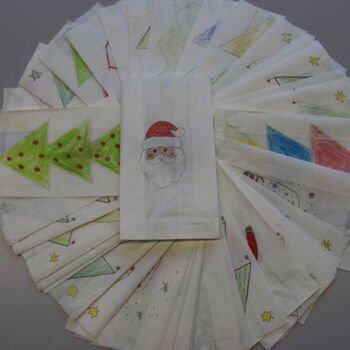 Ein Fächer aus bemalten Weihnachtstüten zeigt Motive wie Weihnachtsbäume und einen Weihnachtsmann.