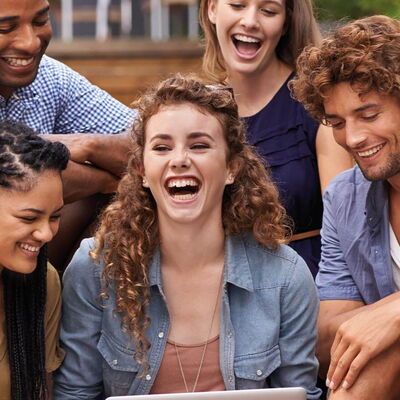 5 junge Leute sitzen lachend beieinander