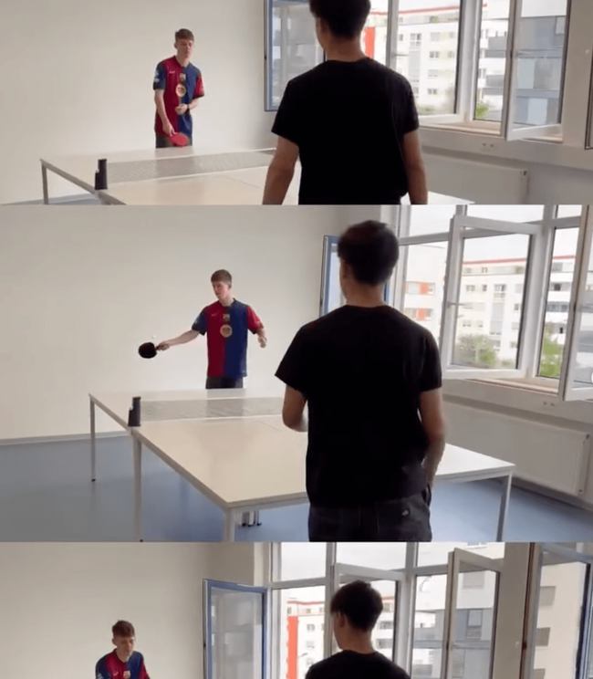 Zwei Jungs spielen Tischtennis in einem hellen Raum mit großen Fenstern, während einer den Ball schlägt.