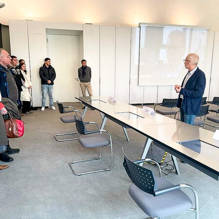 Ein Mann hält eine Präsentation vor einer Gruppe von Menschen in einem modernen Konferenzraum.
