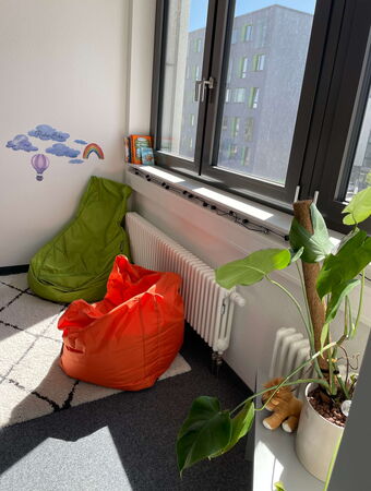 Ein gemütlicher Raum in der Grundschule mit bunten Sitzsäcken, Pflanzen und einer ruhigen Ecke zum Entspannen.
