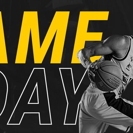 Ein Basketballspieler der MHP RIESEN dribbelt kraftvoll, während "Game Day" in großen gelben Buchstaben erscheint.