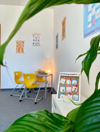 Ein einladendes Büro der Schulsozialarbeit in der Grundschule Flugfeld mit gelben Stühlen und Informationsmaterialien.
