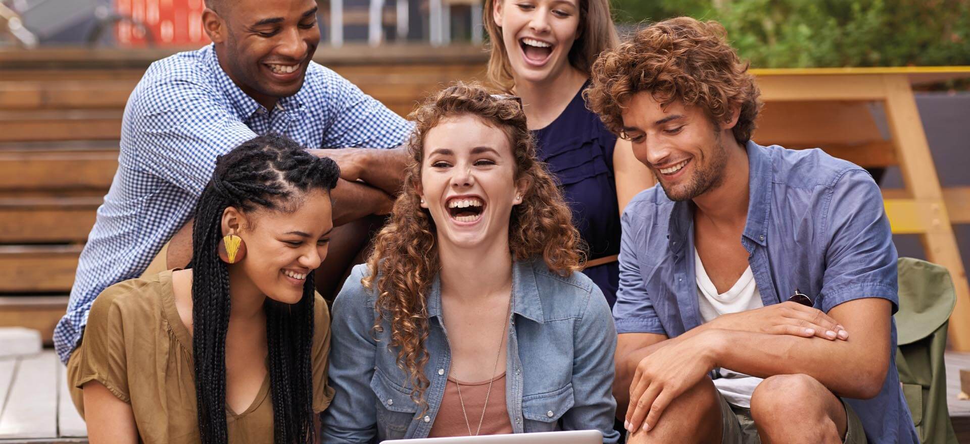 5 junge Leute sitzen lachend beieinander