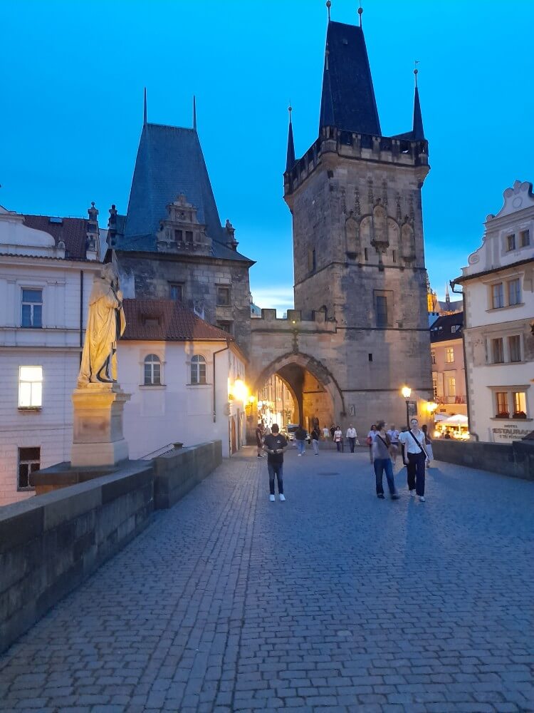 Die Karlsbrücke zeigt Menschen, die bei Dämmerung die historische Architektur bewundern.