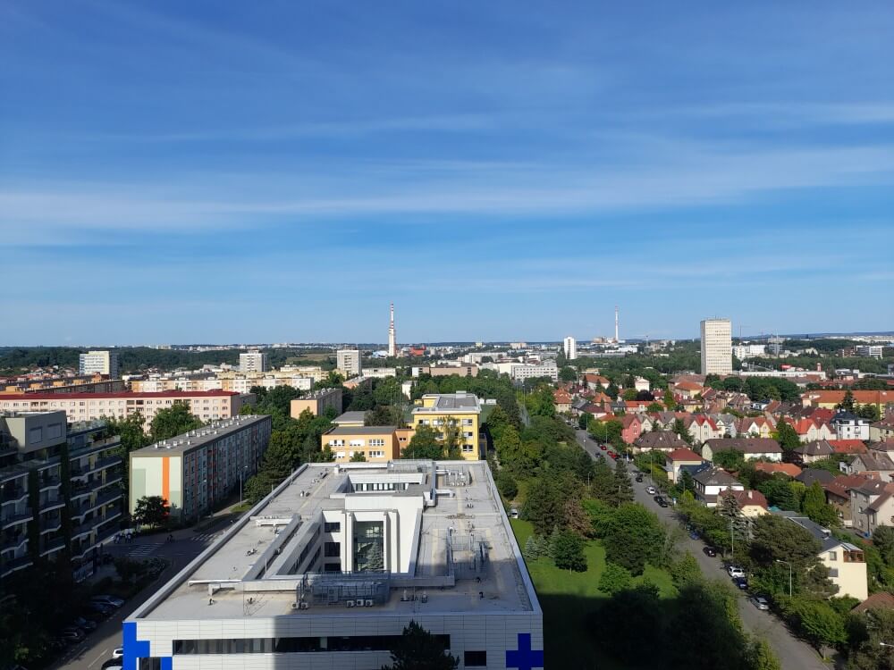 Blick über die Stadt mit grünen Bäumen, modernen Gebäuden und dem klaren Himmel auf IMG_5924.