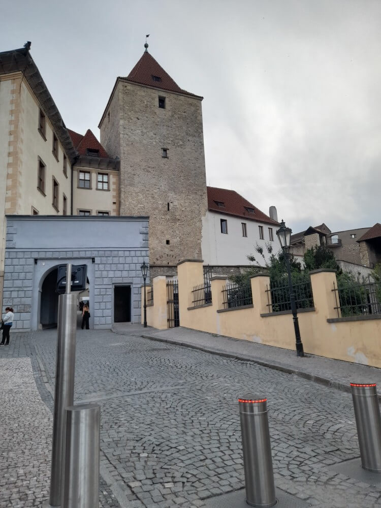 Die historische Mauer und der Turm sind Teil eines alten Gebäudes in einer gepflasterten Straße.