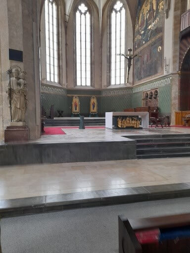 Der Innenraum einer Kirche mit einem Altar, hohen Fenstern und kunstvollen Wandmalereien.