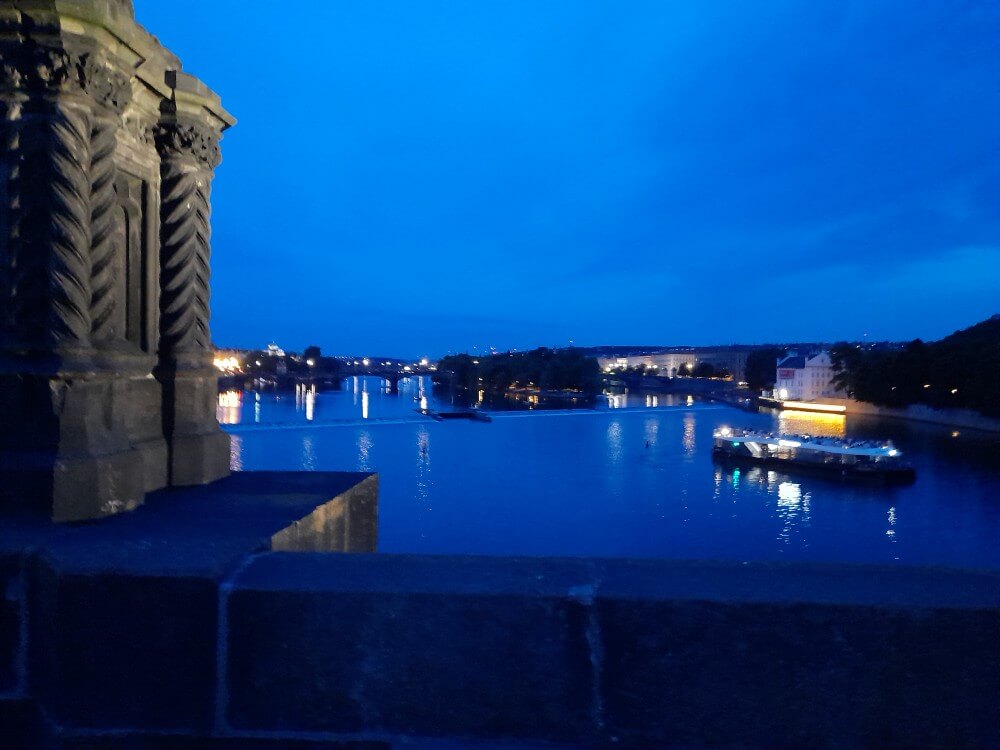 Blick auf den Fluss bei Nacht mit beleuchtetem Boot und Stadtlichtern im Hintergrund, IMG_5962 inspiriert.