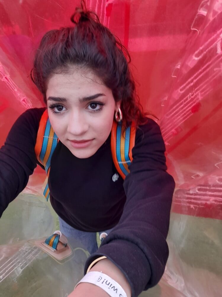 Ein Mädchen mit Rucksack posiert in einer roten Umgebung, die aus transparentem Material besteht.