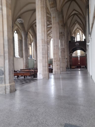 Ein heller Kirchenraum mit hohen Gewölben und Bänken, der eine ruhige Atmosphäre ausstrahlt.